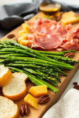 Indulge in a beautifully arranged charcuterie board with vibrant asparagus, savory cured meats, assorted cheeses, and freshly toasted bread, ideal for sharing with friends