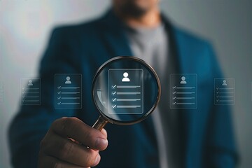 Businessman holding magnifying glass with floating candidate profile icons,digital recruitment and resume screening technology for human resource selection and job talent search process