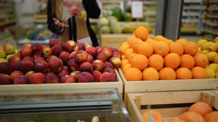 Customer choosing fresh apples and oranges in supermarket