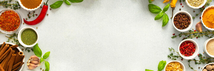 A wide selection of cooking spices and herbs on a gray background, perfect for adding depth to any dish, top view and copy space, banner
