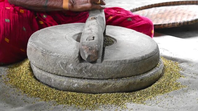 stone quern or hand chakki, making moong dal from whole moong pulses. traditional way of grinding or crushing the grains