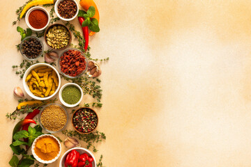 Spread of spices and herbs on a beige surface, featuring essential cooking ingredients for flavorful, home-cooked recipes, top view and copy space