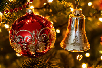 Vintage Christmas tree background with red ball, golden bell and festive lights, selective focus