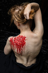 Red wax on back of young submissive woman. Close up.