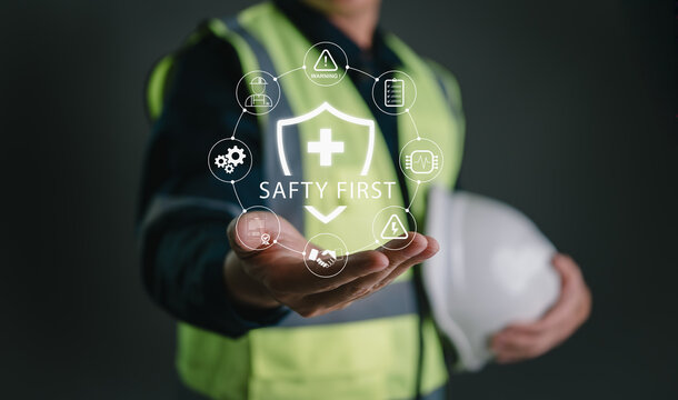 Engineer presenting safety first icon with digital circular interface, surrounded by industry safety symbols, representing occupational health, hazard prevention, and smart workplace protection.