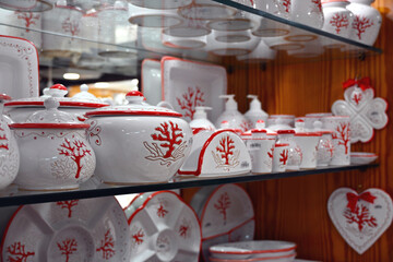 Ceramic products on a store shelf with a red coral motif, one of the symbols of Sardinia, Italy