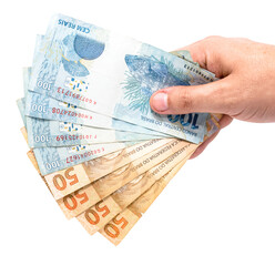 hand holding Brazilian money banknotes, 100 Brazilian real notes, concept of payment, prize or lottery. Isolated white background