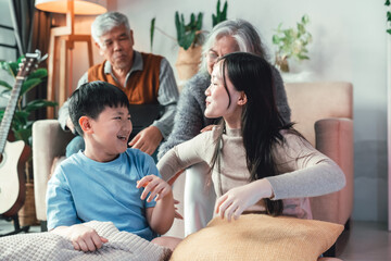 Asian Brother and Sister Laughing with Grandparents in Modern Home Living Room Creating Joyful Family Bonding, Playful Childhood, and Intergenerational Connection