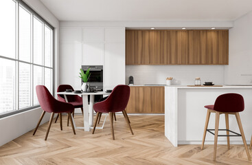 Modern kitchen interior with wooden cabinets, red upholstered chairs, and herringbone parquet floor in bright room with large windows. 3D Rendering