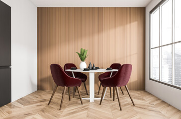 Contemporary dining room interior featuring red upholstered chairs, round white table, wood panel wall, and herringbone floor in natural daylight. 3D Rendering