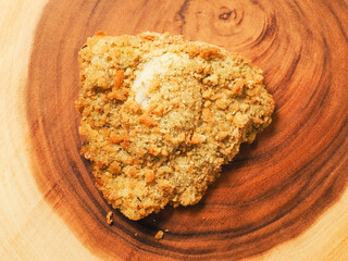 Breaded chicken breast fillet on a wooden board. Classic poultry product. Uncooked meat covered with golden breadcrumbs.