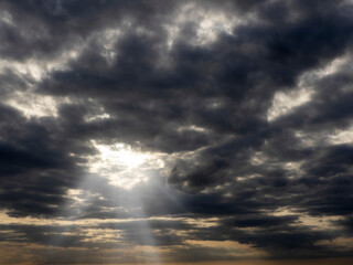 Dark and dramatic cloudy sky with sun beams. Nature background for design.