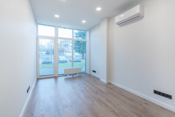 Obraz premium Modern Small Room Interior with Wooden Flooring and Large Glass Window View. AC on the Wall.
