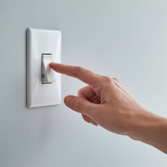 Finger turning on the light switch for a brighter future, saving energy, reducing carbon footprint and making a difference