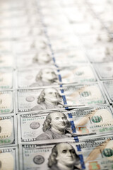 A close view of numerous one hundred dollar bills laid out in an organized manner on a flat surface. This showcases the seriousness of financial matters.
