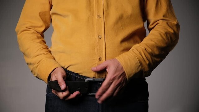 Middle-aged man unbuckles and refastens his belt