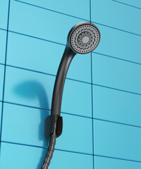 Black shower head on blue tiled bathroom wall