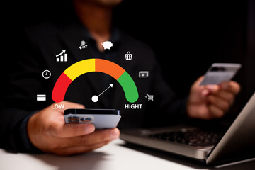 A person using a smartphone displays a performance gauge, indicating levels of achievement, with a laptop in the background.