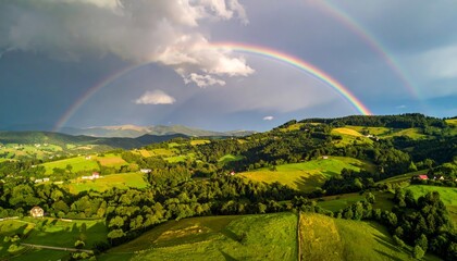 Obraz premium countryside hilly landscape with dark clouds and a vibrant rainbow