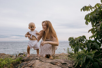 Caucasian woman with child enjoying beach on rocky shoreline