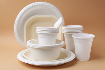 Set of disposable plastic tableware on beige background, closeup