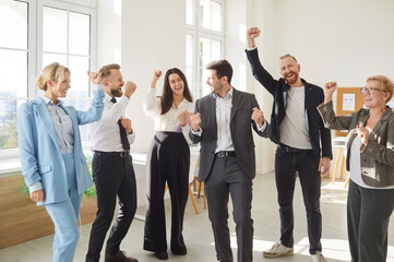 Portrait of a group of joyful happy business people men and women having fun standing in office. Company employees team or a group of staff happy to make a good deal. Teamwork and success concept.
