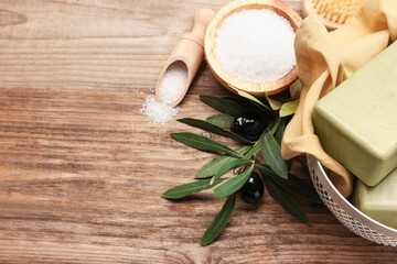 Natural soap bars, olives and sea salt on wooden table, above view. Space for text