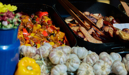 Street food. Market stall. Vegetables stew and fried sausages on a baking sheet. Garlik, pepper. Market Square. Krakow, Poland, Rynek Glowny.