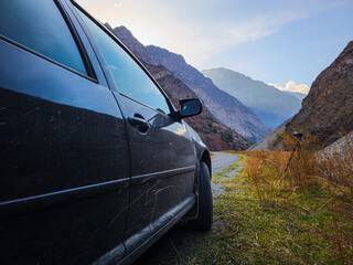 car on gravel road with camera on a tripod in mountainous region
