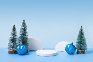 Winter background with cylindrical empty podium display for promotions and for showing product decorate. Stage pedestal or platform between Xmas trees on blue table. Merry Christmas celebration.