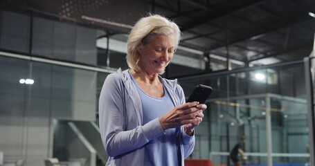 Padel court, mature woman and phone for health stats, message and fitness break. Smile, tennis and person with mobile at sports club for online communication, wellness info or typing text on internet - Powered by Adobe