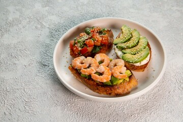 Bruschetta with avocado, shrimp, tomatoes, guacamole, cream cheese and herbs. Healthy eating.