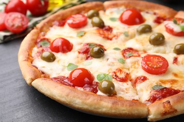 Delicious pizza with cheese, tomatoes and olives on dark grey table, closeup