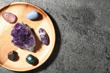 Different beautiful gemstones on grey table, top view. Space for text