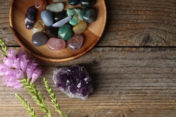 Different beautiful gemstones and flowers on wooden table, flat lay. Space for text