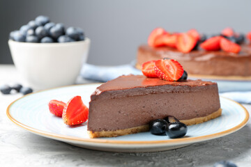 Piece of tasty chocolate cheesecake with berries on light grey textured table, closeup