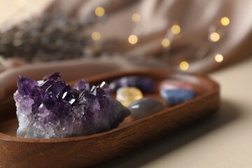 Different beautiful gemstones on beige table, selective focus