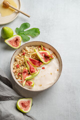 Natural yogurt with granola, figs and honey in a bowl on a light background