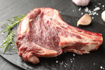 Piece of raw beef meat and spices on black table, closeup