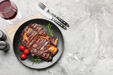 Delicious grilled beef steak with rosemary, onion and tomatoes served on grey textured table, flat lay. Space for text