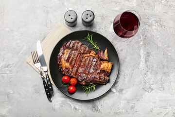 Delicious grilled beef steak with rosemary, onion and tomatoes served on grey textured table, flat lay