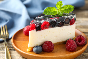 Piece of delicious cheesecake with berries and mint on wooden table, closeup