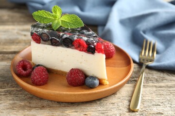 Piece of delicious cheesecake with berries and mint on wooden table, closeup