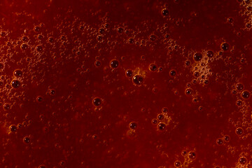 Abstract macro shot of red liquid with bubbles, ideal for background or design.