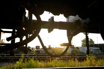Industrial landscape framed by metal structural elements at sunset, with green grass in the foreground, highlighting contrast between nature, infrastructure and industrial environment.