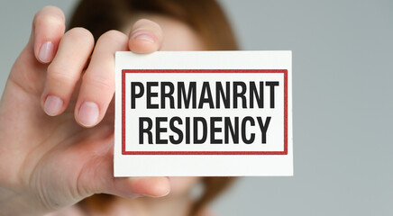 A person is holding a card that says Permanent Residency