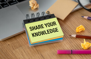 Share Your Knowledge inscription on open notebook with colored pens and pencils with laptop on wooden background