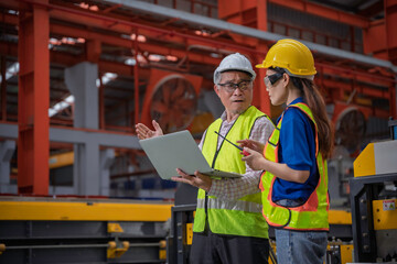 Engineer and technician inspecting materials on factory production line while discussing data on laptop. Great for industry, manufacturing, teamwork, and quality control concepts.