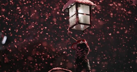 Christmas background with snowfall in slow motion. A person is holding a cup of hot wine under lantern in the snow. The lantern is lit and the snow is falling around it. - Powered by Adobe