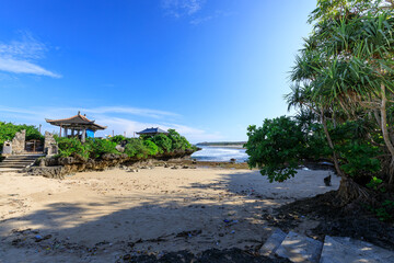 Beach with a small pavilion and a tree in the background
